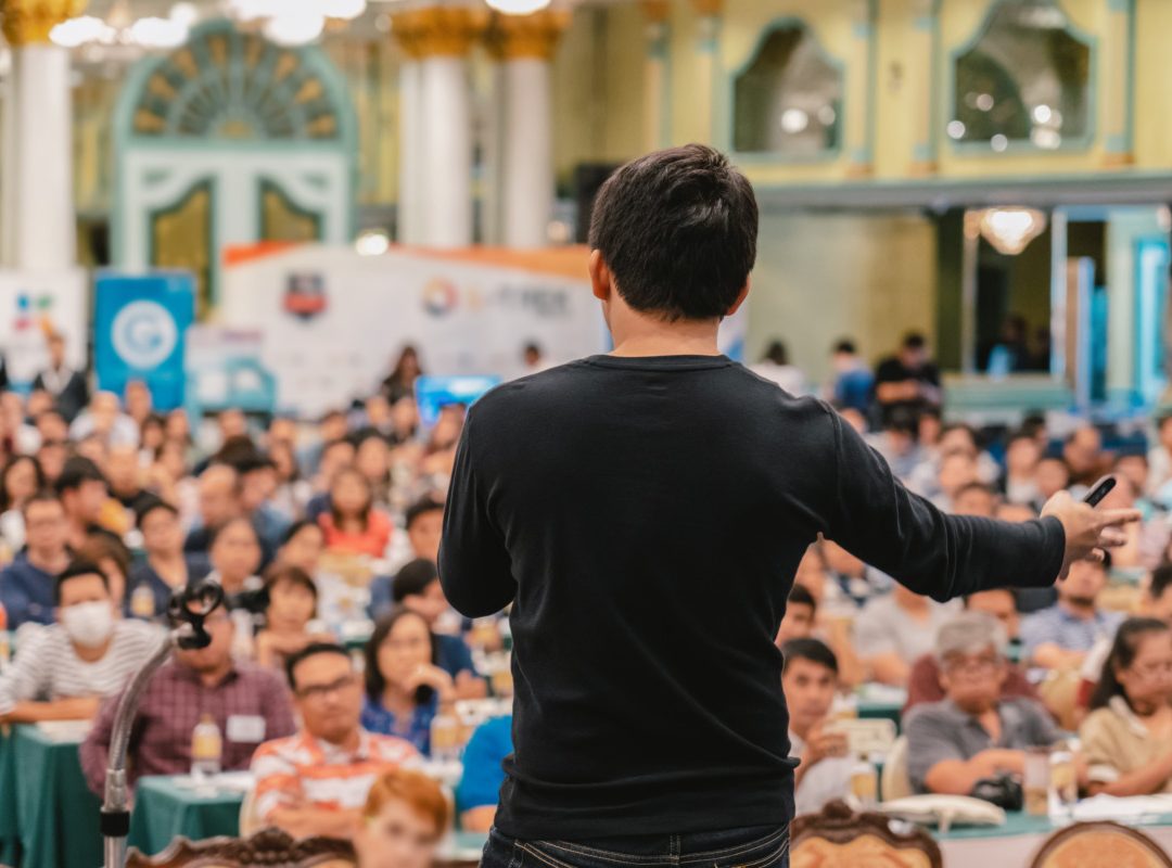 Rear view of Asian Speaker with casual suit standing and giving